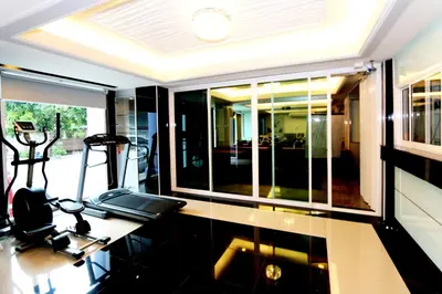 a room with a table with a treadmill and windows at T3 Residence in Bangkok