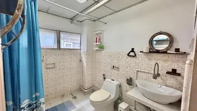 a bathroom with a toilet and a sink and a mirror at Café de Baan Raow in Bangkok