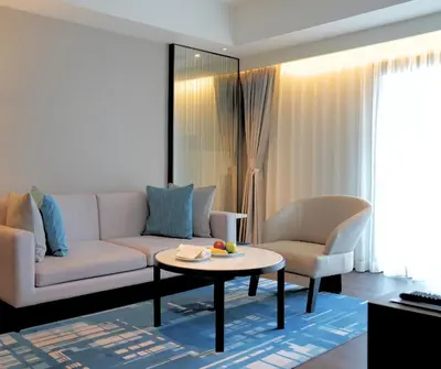 a living room with a couch and a table and chairs at Marriott Executive Apartments Bangkok, Sukhumvit 50 in Bangkok