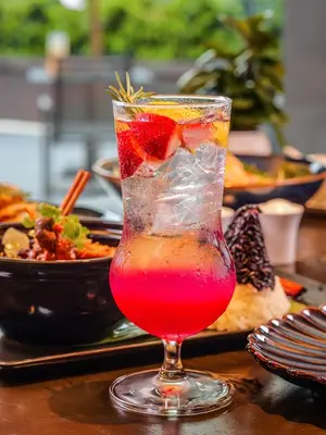a drink with a strawberry in a glass on a table at Marriott Executive Apartments Bangkok, Sukhumvit 50 in Bangkok