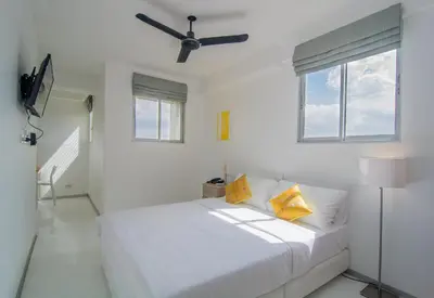 a white bedroom with a bed and a ceiling fan at ST88 Residence in Nonthaburi
