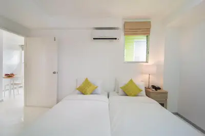 a white bedroom with two beds and a window at ST88 Residence in Nonthaburi