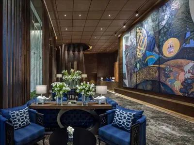 a lobby with a table and chairs and a mural at 137 Pillars Residences Bangkok in Bangkok