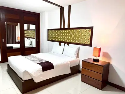 a bedroom with a bed and a table with a lamp at ลีลาวดี รามอินทรา - Leelawadee Resotel Raminthra 23 in Bangkok