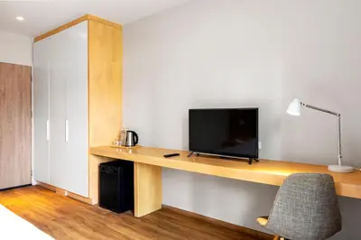 a room with a desk with a television and a chair at Nest by Sangob in Bangkok