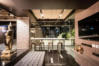 a lobby with a bar with stools and a statue at Fyn Hotel in Bangkok