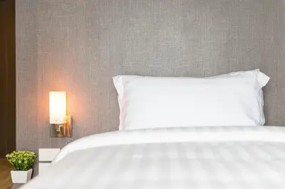 a white bed with a white pillow and a lamp at Fyn Hotel in Bangkok