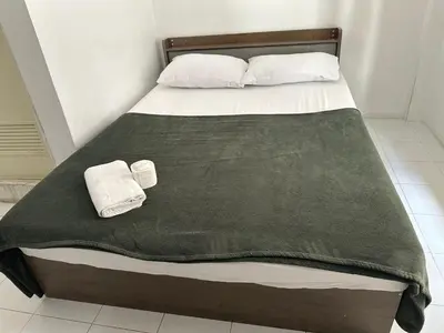 a bed with a green blanket and two towels on it at Bann Bunga Inn in Bangkok