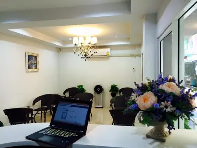 a laptop sitting on a table with a vase of flowers at Bann Bunga Inn in Bangkok