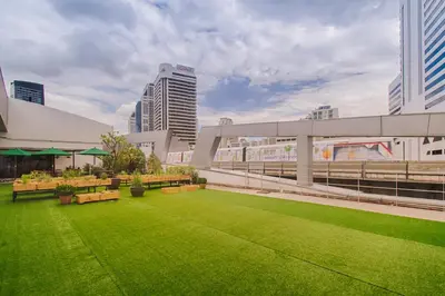 a courtyard with benches and grass in a city at Hom Hostel & Cooking Club in Bangkok
