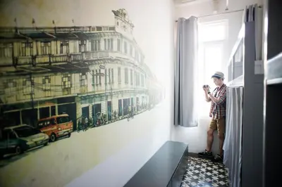 a man standing in a room looking out a window at Cacha Bed in Bangkok