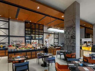 a restaurant with tables and a chef in the kitchen at Mercure Bangkok Makkasan in Bangkok