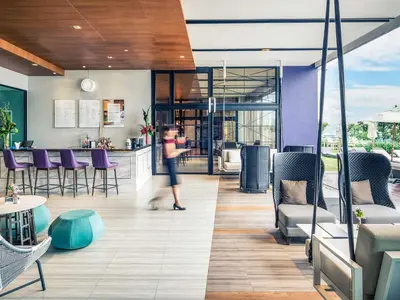 a woman is standing in a room with a kitchen at Mercure Bangkok Makkasan in Bangkok