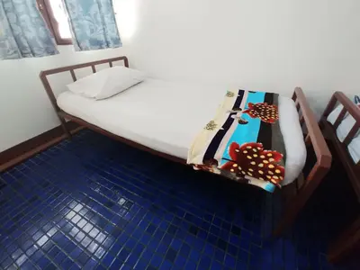 a bed in a room with two chairs at Prasuri Guest House in Bangkok