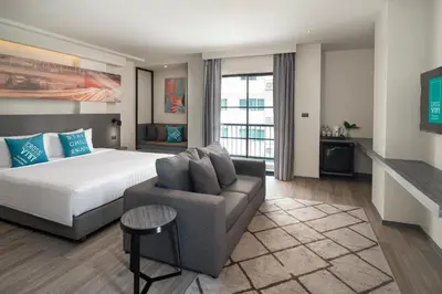 a hotel room with a bed and a couch at Cross Vibe Bangkok Sukhumvit in Bangkok