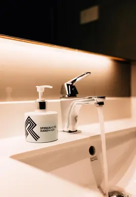 a bathroom sink with a bottle of soap on it at Spenza Hotel in Bangkok