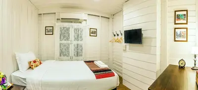 a small bedroom with a bed and a tv at Baankachitpan Bangkok Hotel in Bangkok