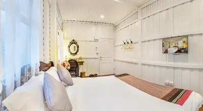 a bedroom with a white bed and a fireplace at Baankachitpan Bangkok Hotel in Bangkok