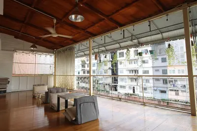 a large room with a table and chairs and large windows at Baan Nampetch Hostel in Bangkok