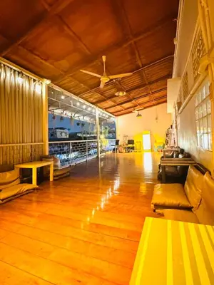 a large room with wooden floors and a couch and a table at Baan Nampetch Hostel in Bangkok