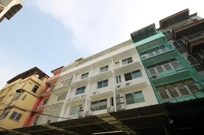 a tall white building with colorful windows at Baan Nampetch Hostel in Bangkok