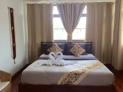 two white swans sitting on a bed in front of a window at Naturbliss Resort Village in Bangkok