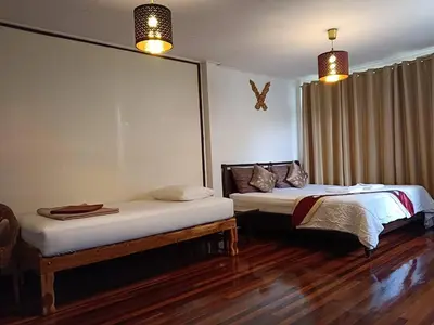 two beds in a room with wooden floors at Naturbliss Resort Village in Bangkok