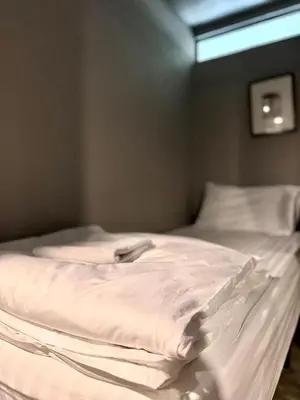 an unmade bed with white sheets and a window at Collection O The Spades Hostel in Bangkok
