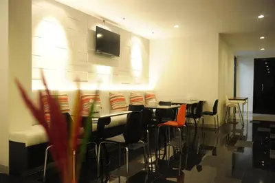 a restaurant with tables and chairs with a tv on the wall at Leenova Hotel in Bangkok