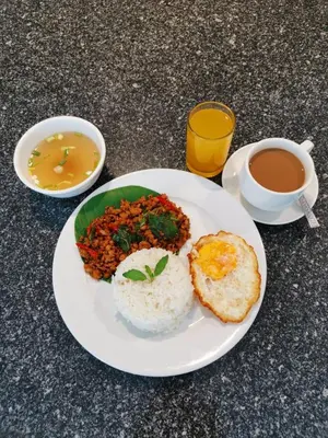 a plate of food with eggs and rice and a cup of coffee at Leenova Hotel in Bangkok