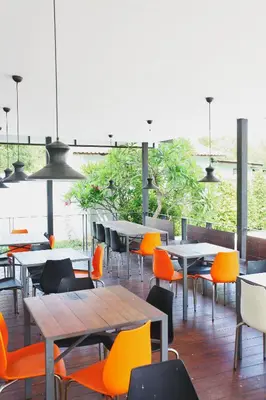 a restaurant with tables and chairs with orange chairs at Leenova Hotel in Bangkok