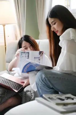 a woman sitting on a couch with a girl reading a book at Noursabah Boutique Bed Bangkok in Bangkok