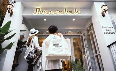 a man walking into a store with a bag on his back at Noursabah Boutique Bed Bangkok in Bangkok