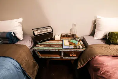 a room with two beds and a table between two beds at Sor Vorapin Muay Thai Home in Bangkok