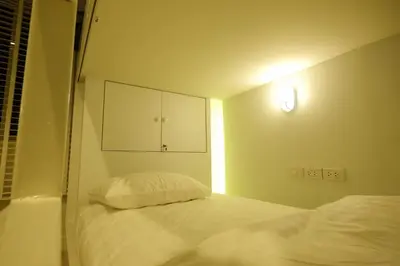 a small bedroom with a bed and a cabinet at Ratana Boutique Hostel in Bangkok