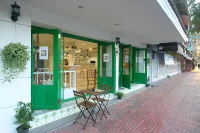 a table and chairs outside of a store with green doors at Ratana Boutique Hostel in Bangkok