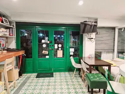 a green door in a room with a table and chairs at Ratana Boutique Hostel in Bangkok