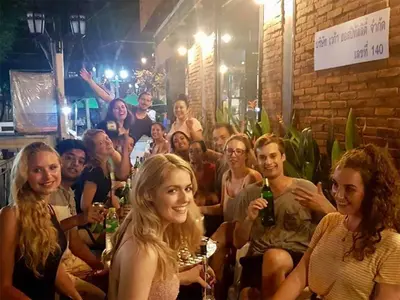 a group of people sitting in a bar with drinks at The Printing House Poshtel in Bangkok