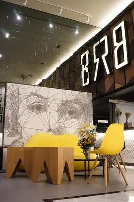 a yellow table and two chairs in front of a wall at BRB Hostel Bangkok Silom in Bangkok