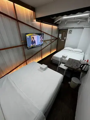 a hotel room with two beds and a flat screen tv at Glur Central Pratunam in Bangkok