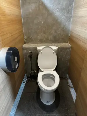 a bathroom with a toilet and a toilet paper dispenser at Glur Central Pratunam in Bangkok