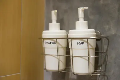 a rack with three bottles of soap in a bathroom at Barn & Bed Hostel in Bangkok