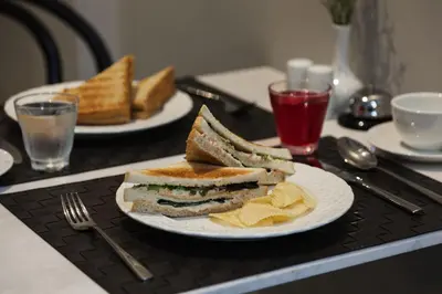 two plates of sandwiches and chips on a table at Oriental Heritage Hotel in Bangkok