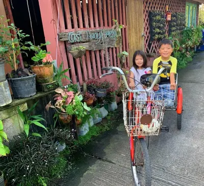 a boy and girl sitting on a bike next to a shop at Cast Away in Nonthaburi