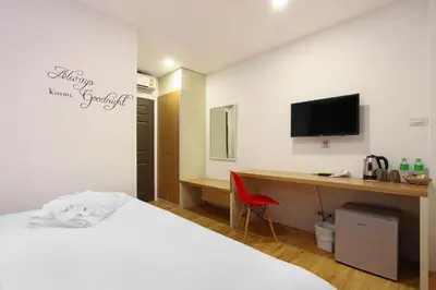 a hotel room with a bed and a desk with a computer at Pula Silom in Bangkok