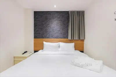 a bedroom with a white bed and a brick wall at Pula Silom in Bangkok