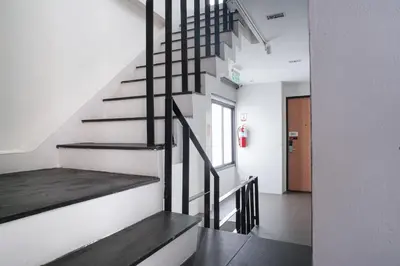 a hallway with stairs in a building with a fire extinguisher at Marwin Space in Bangkok