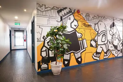 a plant in a pot in a hallway with a mural at Marwin Space in Bangkok