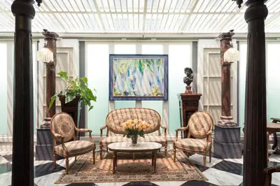 a living room with chairs and a table and a painting at Sara's Hotel in Bangkok