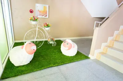 two sheep sitting on a patch of grass next to stairs at A18 in Nonthaburi